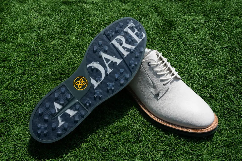 White G/FORE x Adare Manor golf shoe on grass with navy ADARE-branded sole