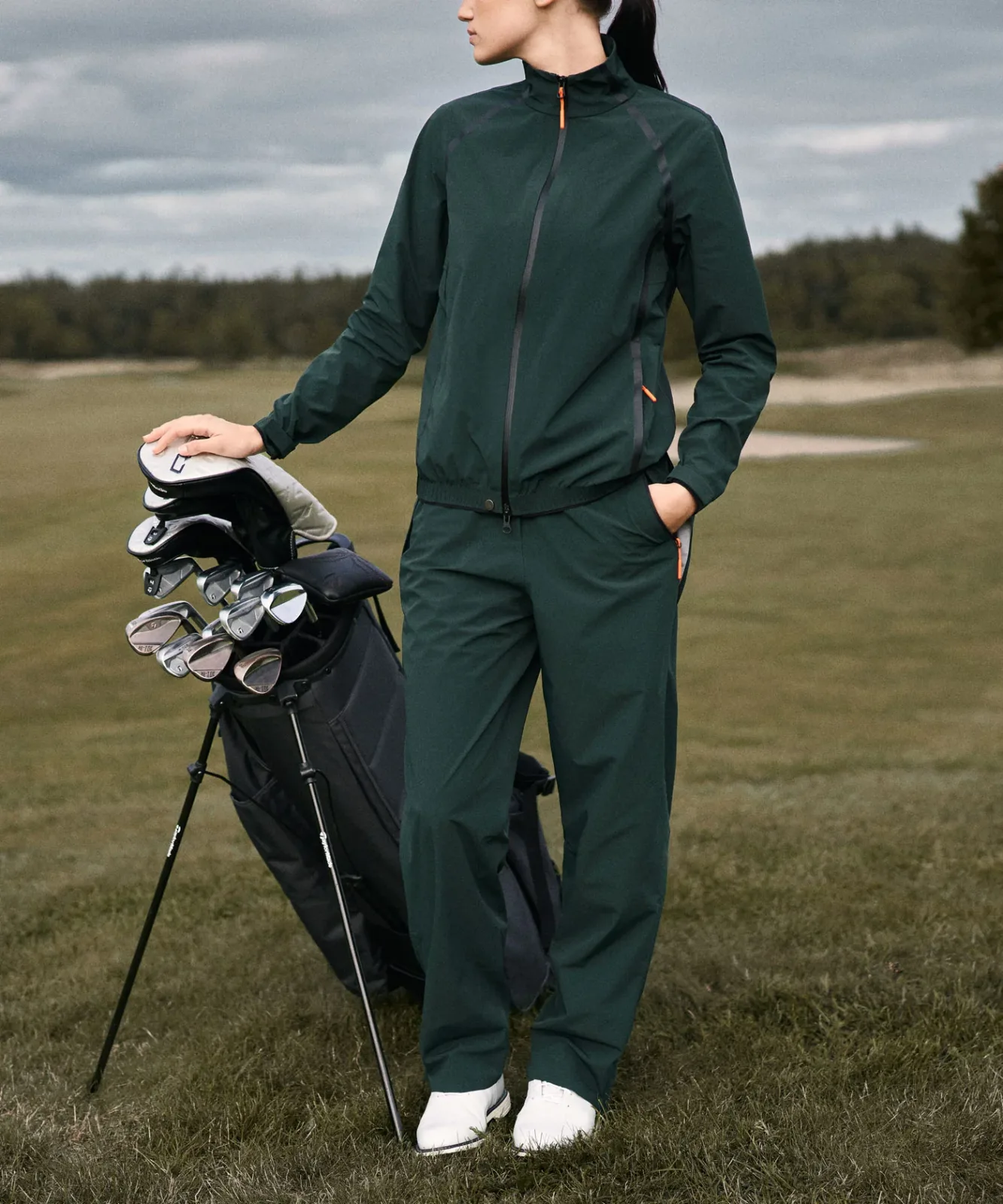 Woman in the green HydroCore jacket and trousers on a links course